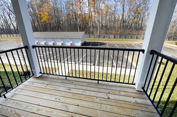 A balcony with a view of a parking lot and trees